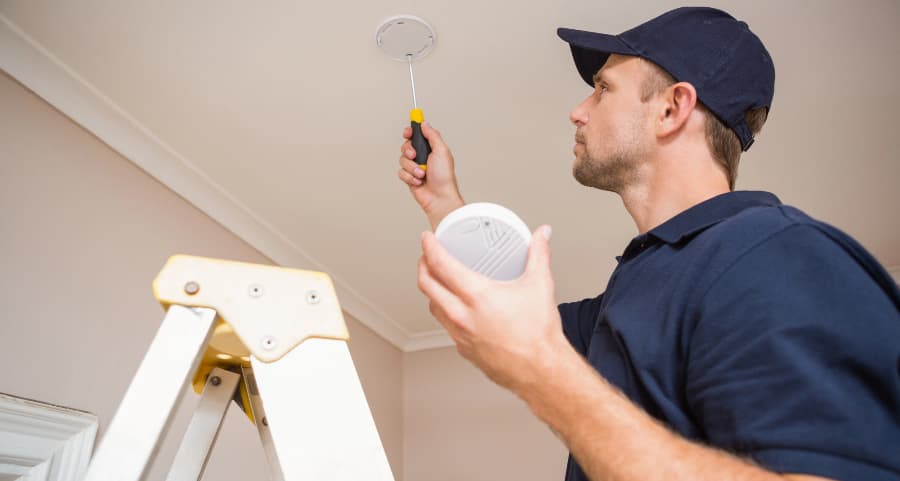 Man installing smoke detector on ceiling of home